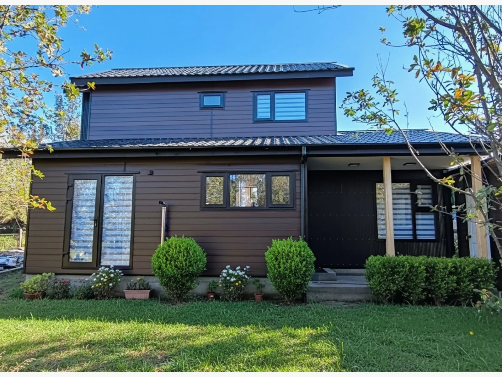 Vivienda de dos pisos con revestimiento de madera y jardín